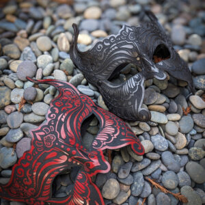 Red and black masks on pebbles.