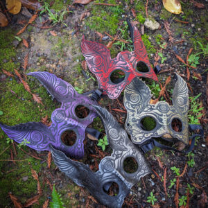 Colorful ornate masks on forest floor.